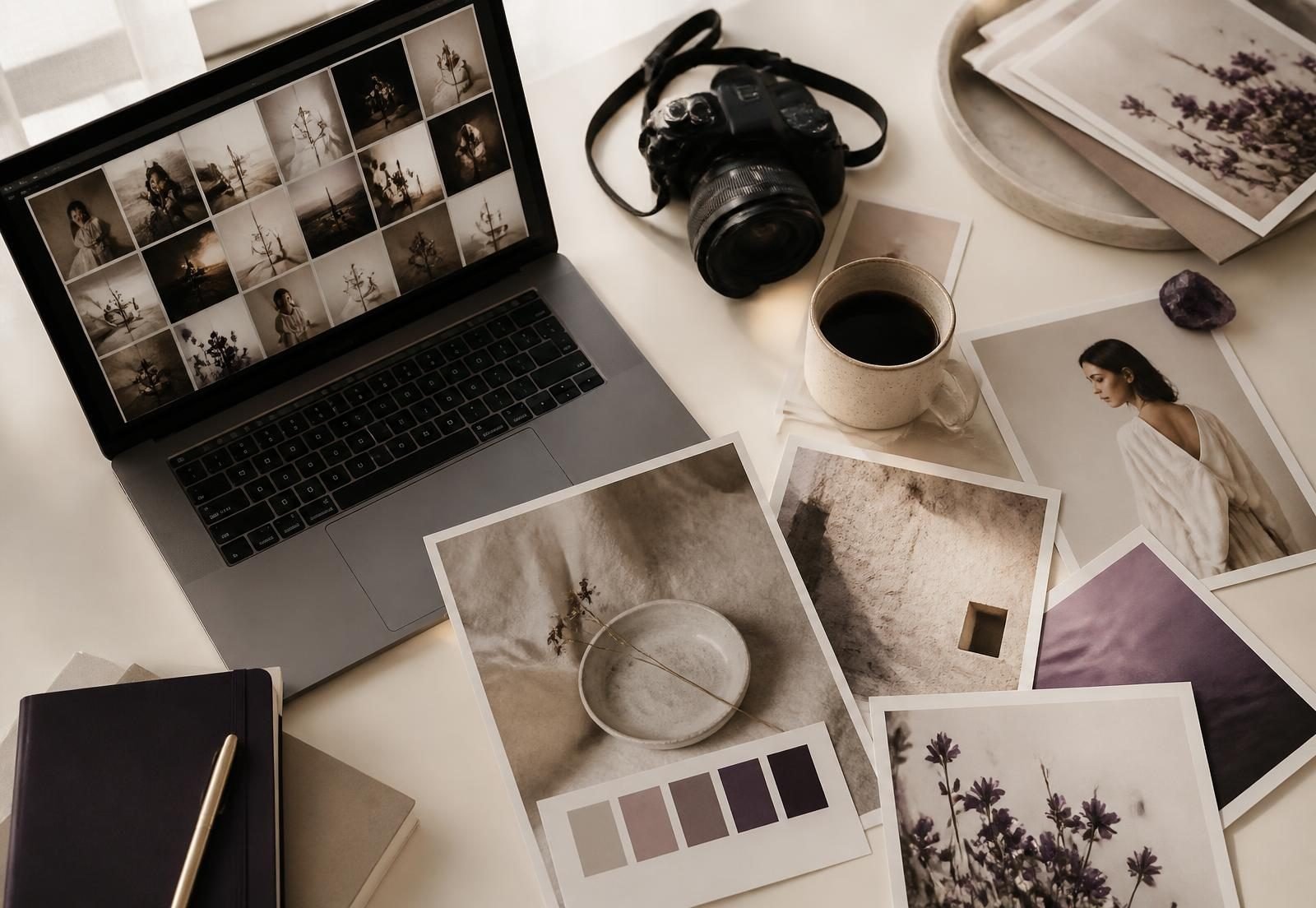 A photographer's desk with a laptop showing a photo catalogue, a camera and printed images